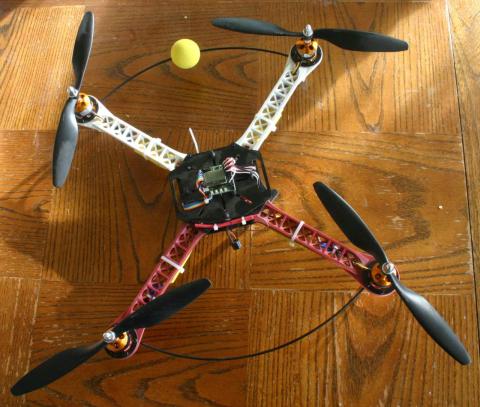 A picture of a red and white X-layout quadcopter with black props