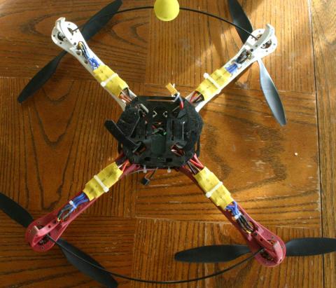 A bottom view of a red and white quadcopter, with black props