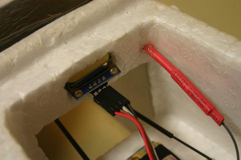 A GPS module stuck into the styrofoam body of a model plane